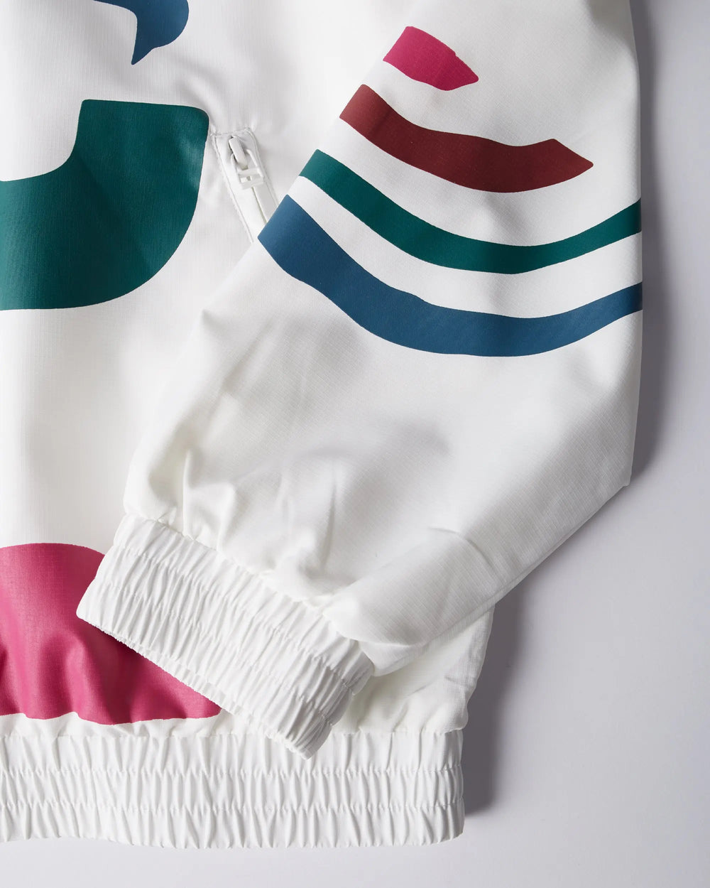 Close-up detail of the white byParra Tennis Maybe? track jacket sleeve with colorful graphics and elastic cuffs.